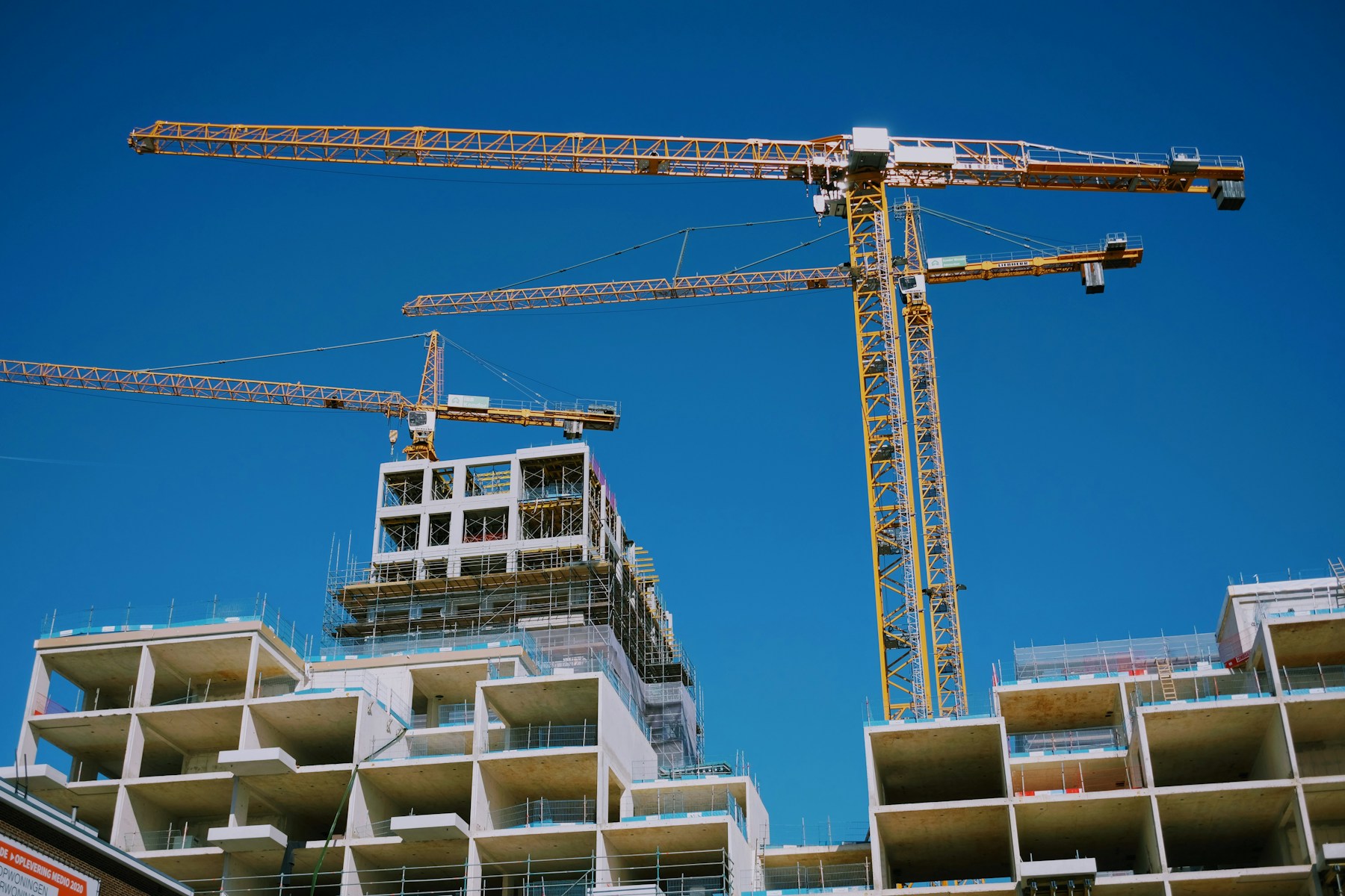 Golden construction cranes against a deep blue sky